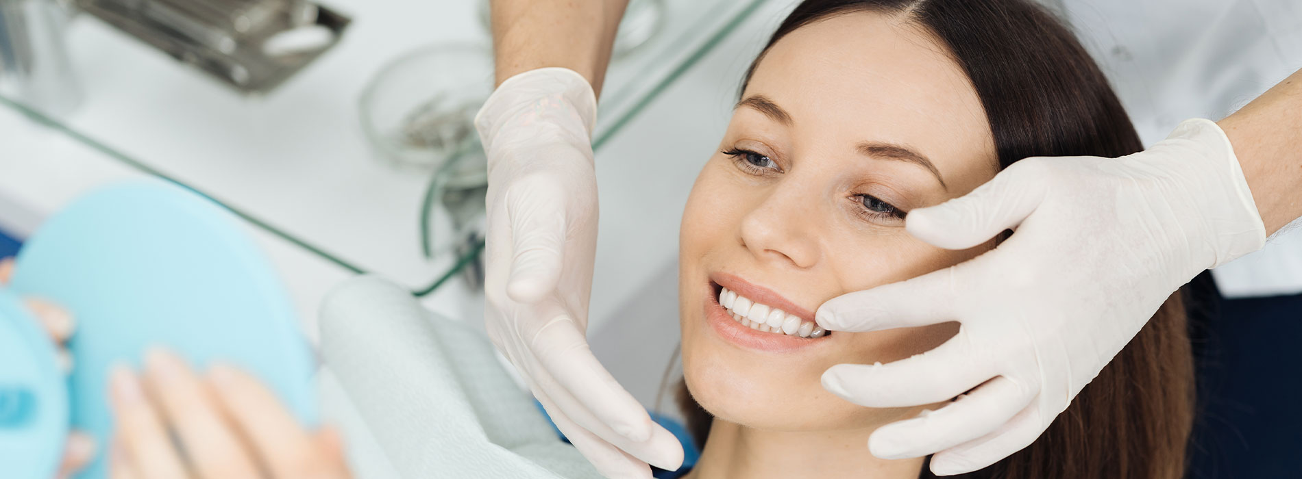 A woman receiving cosmetic treatment with a medical professional, both wearing protective gloves and masks, in a clinical setting.