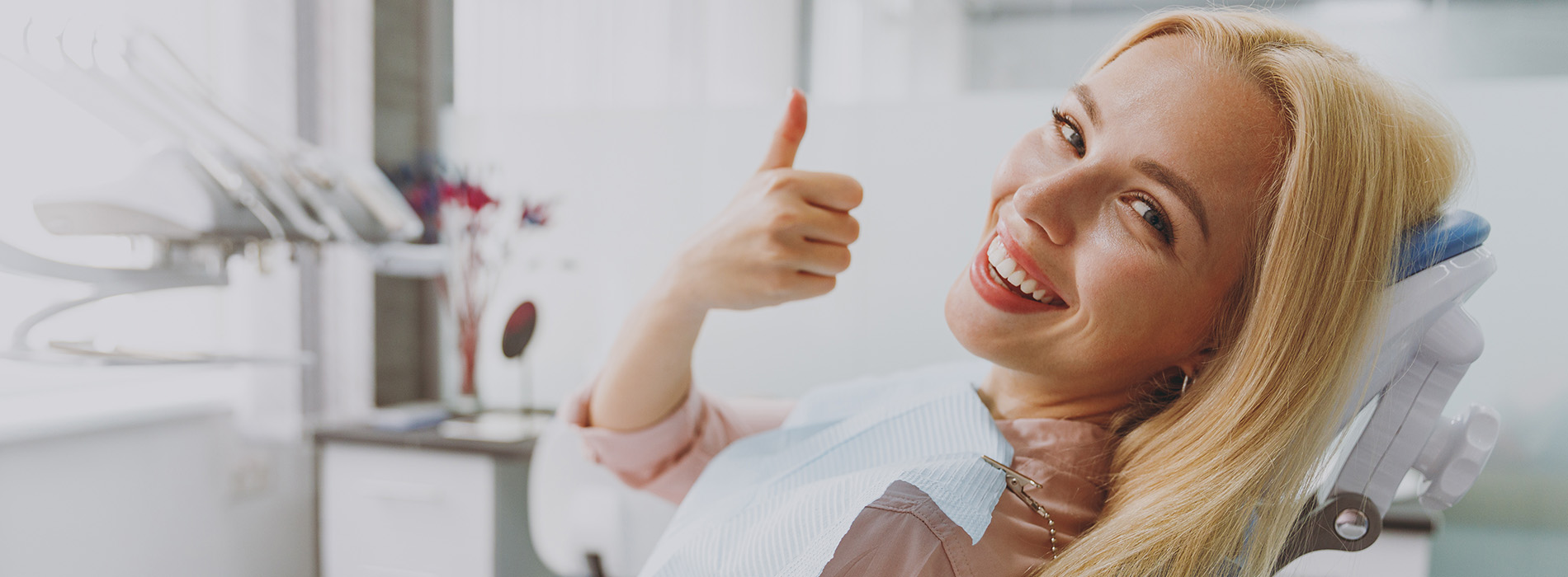 The image shows a group of people, possibly professionals given their attire and the setting that appears to be an office or professional environment. They are gathered around a table with a laptop on it, engaged in what seems to be a discussion or meeting.