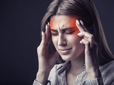 The image displays a woman with her hands on her head, appearing to be experiencing discomfort or pain, with a red light emanating from the top of her head, suggesting she may be undergoing some kind of scanning or medical procedure.