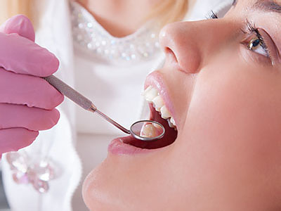 A woman receiving dental treatment while a dental professional performs the procedure.