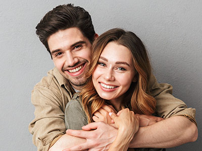 A young man and woman hugging each other with smiles on their faces.